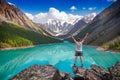 Young hiker standing with raised hands near the beautiful mountain lake and enjoying valley view Royalty Free Stock Photo