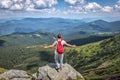 Young hiker tourist traveler on a mountain top in summer, with his back with a backpack