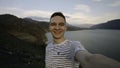 Young hiker traveler man taking selfie at mountain top. Action. Young happy man with mountains and beautiful lake on the Royalty Free Stock Photo