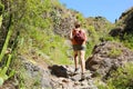 Young hiker woman with backpack climbs steep rocky terrain