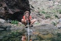 Young hiker woman drinking stream water in mountain