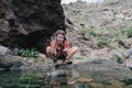 Young hiker woman drinking stream water in mountain