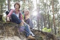 Young hiking couple sitting on edge of cliff in forest