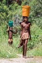 Young Himba woman carries a bucket