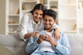 Hindu couple sharing a moment, looking at smartphone on couch