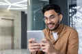 Young Hindu programmer close up inside office using application on tablet computer, male developer testing new software