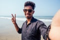 Young hindu stylish man taking a picture self portrait on the smartphone front camera with sunglasses active beach Royalty Free Stock Photo