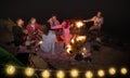 Young hippie friends having fun together at night beach party with string light - Friendship travel concept with young people