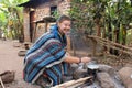 Young hippie woman in a blue poncho cooking on a campfire campground in an village Royalty Free Stock Photo