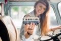 Young hippie woman driving a classic van with a toy car model in her hand. Smiling blurred girl holding a miniature Royalty Free Stock Photo