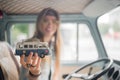 Young hippie woman driving a classic van with a toy car model in her hand. Smiling blurred girl holding a miniature Royalty Free Stock Photo