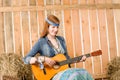 Young hippie woman play guitar in barn