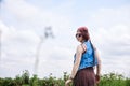 Young hippie woman with short red hair, wearing boho style clothes and sunglasses, dancing on green currant field, posing for Royalty Free Stock Photo