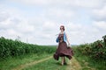 Young hippie woman with short red hair, wearing boho style clothes and sunglasses, dancing running jumping on green currant field Royalty Free Stock Photo