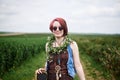 Young hippie woman with short red hair, wearing boho style clothes, sunglasses, with flower wreath on neck, standing on green Royalty Free Stock Photo