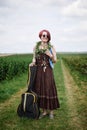 Young hippie woman with short red hair, wearing boho style clothes, sunglasses, with flower wreath on neck, standing on green Royalty Free Stock Photo