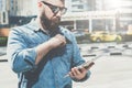 Young hipster bearded businessman in sunglasses stands on city street and uses tablet computer while pulls out credit Royalty Free Stock Photo