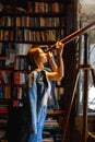 Young hipster female looks through a telescope standing in vintage library room