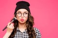 Young hipster girl having fun and going crazy, wearing glasses hat bright make up. Pink urban background. The woman mad Royalty Free Stock Photo