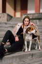 Young hipster girl with her pet estonian hound dog playing and having fun outdoor in the park. Royalty Free Stock Photo