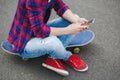 Young hipster girl sitting at skate park and chatting on her phone Royalty Free Stock Photo