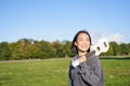 Young hipster girl, traveler holding her ukulele, playing outdoors in park and smiling Royalty Free Stock Photo