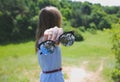 Young hipster girl is travelling in the mountains. Woman in modern dress is holding fashion sunglasses in hands. Trees and sky