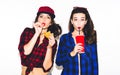 Young hipster girls having fun drinking a soda from straw and holding a burger, happy smile and laugh on the white