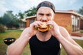 Young hipster guy eating delicious burger outdoors