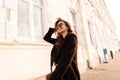 Young hipster happy woman in black sunglasses with a beautiful smile in fashionable spring clothes walks along the street Royalty Free Stock Photo