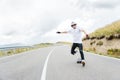 A young hipster in a helmet and gloves performing a slide standing at a high speed falls from the board