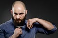 Young hipster man cutting his beard with scissors - grey background