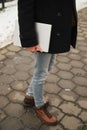 young hipster man with laptop in hand with a urban look in city. in the city winter