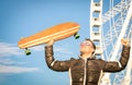 Young hipster man with longboard skate board at luna park