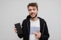 Young hipster man pointing at his phone. Casual guy showing something on his phone screen. Hipster gesturing and smiling with his