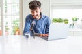Young hipster man recording podcast using laptop, broadcasting an interview using microphone Royalty Free Stock Photo