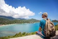 Young hipster man sitting at sea view point with backpack. Travel, adventure, wonderlust, tourism concept. Royalty Free Stock Photo