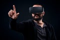 Young hipster man wearing virtual reality goggles. Black background studio VR concept Royalty Free Stock Photo