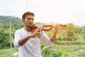 Young hipster musician man playing violin in the nature outdoor lifestyle behind mountain Royalty Free Stock Photo