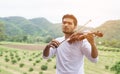 Young hipster musician man playing violin in the nature outdoor lifestyle behind mountain Royalty Free Stock Photo