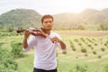 Young hipster musician man playing violin in the nature outdoor lifestyle behind mountain Royalty Free Stock Photo