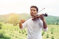 Young hipster musician man playing violin in the nature outdoor lifestyle behind mountain Royalty Free Stock Photo