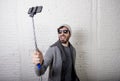 Young hipster trendy blogger man holding stick recording selfie video in vlog concept Royalty Free Stock Photo