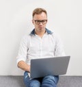 Young hipster using laptop computer while sitting on floor.