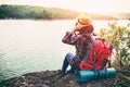 Young hipster woman with backpacker sitting on stone enjoying