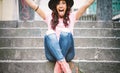 Young hipster woman having fun throwing confetti with her hands - Happy pretty girl celebrating her graduation sitting on stairs