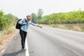 Young hipster woman hitchhiking on countryside road wait for the Royalty Free Stock Photo