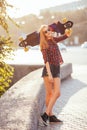 Young hipster woman holding skateboard behind head in sunset, outdoors, cinematic style. Stylish lucky hipster woman Royalty Free Stock Photo