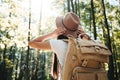 Young hipster woman traveling alone on outdoors among trees and hold hat his hands. Handsome girl wearing traveler backpack Royalty Free Stock Photo