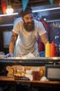 Young hipster working in fast food service, wearing cook hat